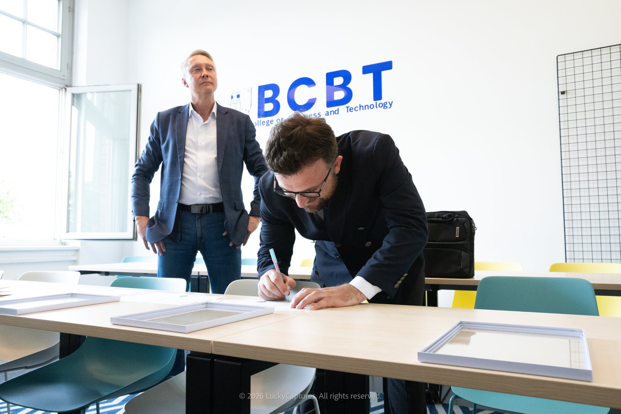 Dr. Valdrin Dervishaj signing certificates, Holger Holland in the background