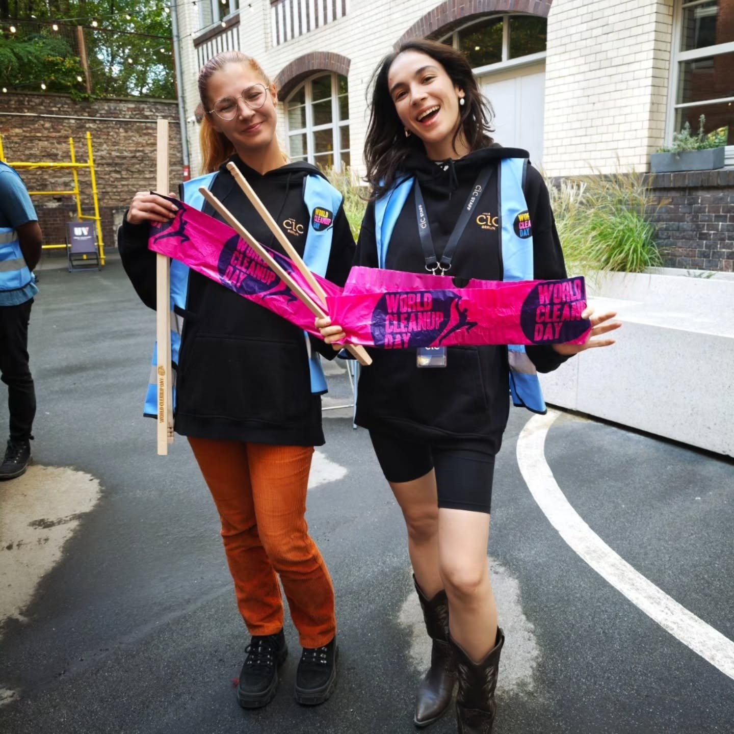 Two participants with litter pickers and pink World Cleanup Day bags